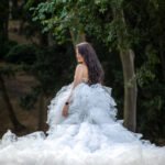 Elegant bride in a voluminous white tulle gown looking over her shoulder in a lush green forest setting in Istanbul